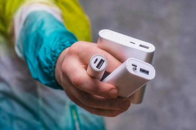 Man houdt een powerbank in zijn handen en laadt een smartphone op tegen een betonnen muur