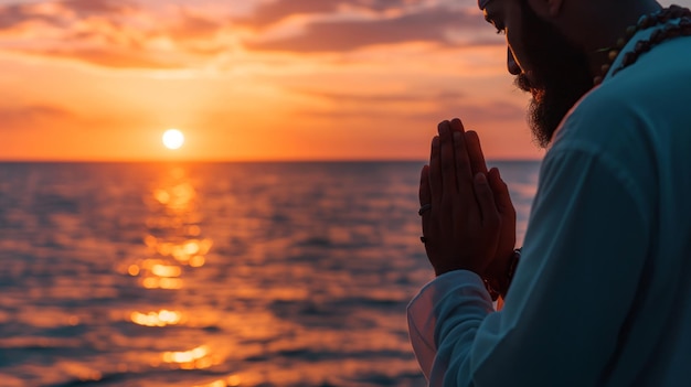 man houdt gebedskralen vast en bidt bij zonsondergang met de rustige oceaan als achtergrond