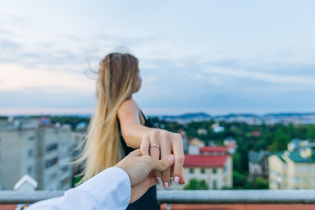 Man houdt het meisje bij de hand en toont ring aan de ringvinger, ze kijkt naar het panorama van de stad