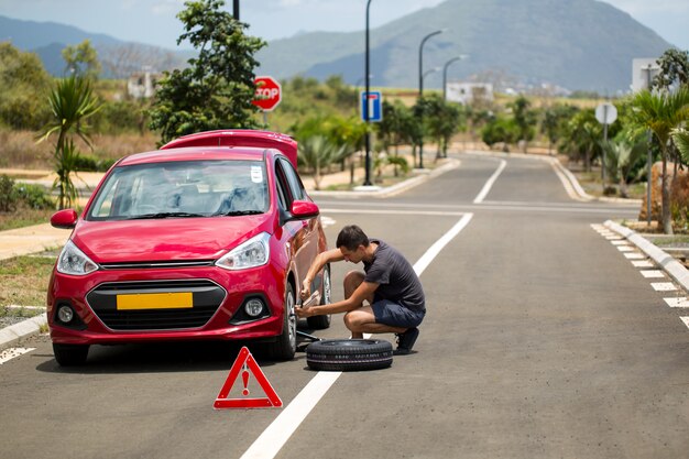 Man houdt het reservewiel tegen een defecte auto