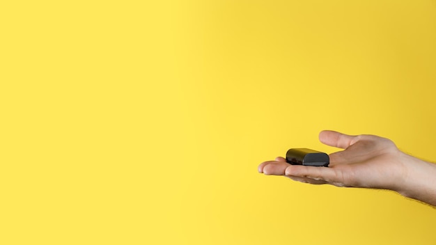 Man houdt in de hand zwarte accu voor dslr op een gele achtergrond Oplaadbare lithiumbatterij