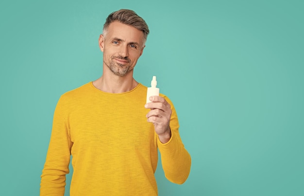 Man houdt neusmedicine geïsoleerd op blauw man houdt neusmedacine in studio