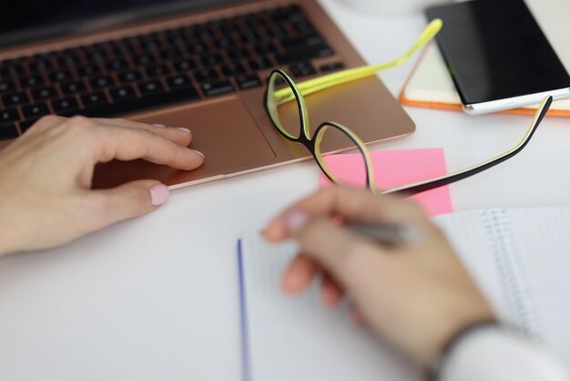 Man houdt pen vast en maakt aantekeningen in notebookplandag werken op laptop