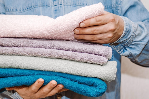 Man houdt stapel verse badstofhanddoeken vast Organiseren en schoonmaken van huis Opslag en huishouden