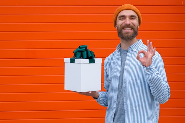 Foto man houdt witte doos met groene strik vast