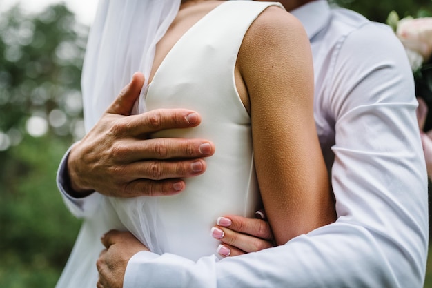 Man hug woman goosebumps appeared on body of a young beautiful\
bride from touch man beautiful skin texture a groom gently embraces\
girl in a wedding dress by the shoulders close up