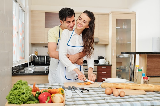 Man hugging cooking girlfriend