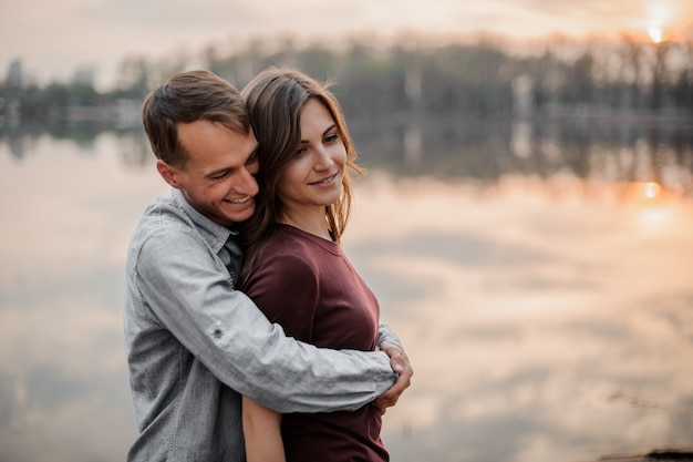 Man hugging from behind his woman on the scene of lake