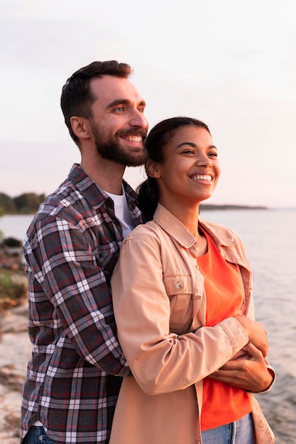 Foto uomo che abbraccia la sua ragazza da dietro mentre guarda il tramonto