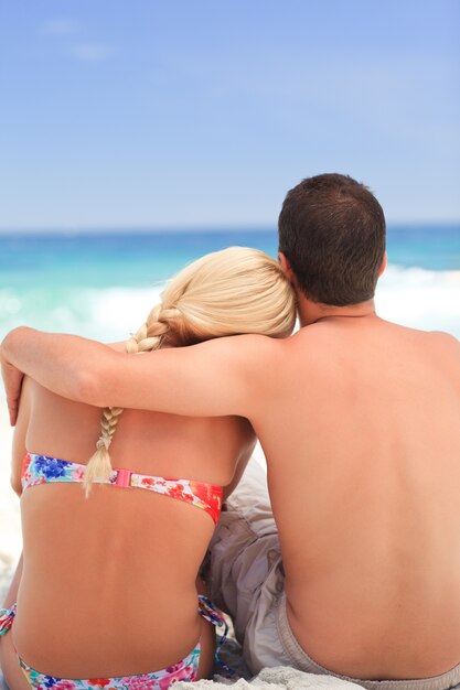 Мужчина обнимает свою девушку, пока они смотрят на море