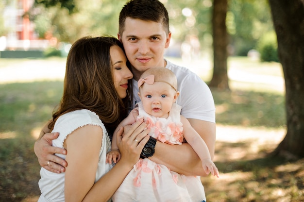 Man hugging his lovely wife and cute little daughter