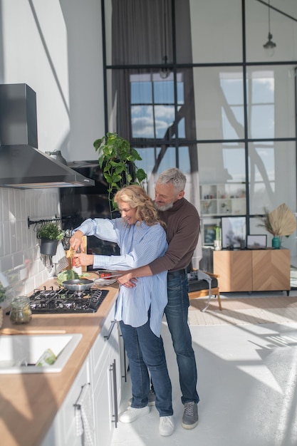 Man hugging his wife while she cooking breakfast