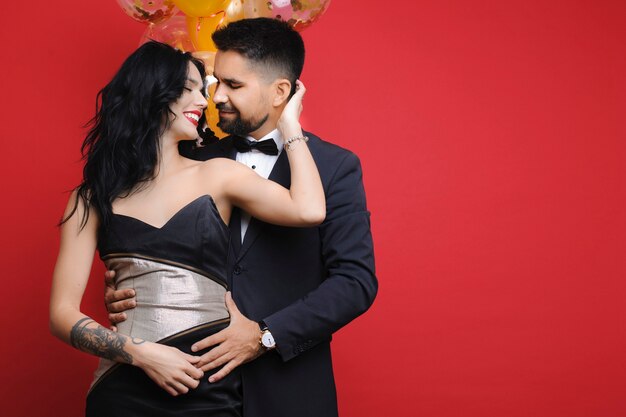 Man hugging his woman near balloons from back