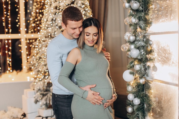 man hugging pregnant woman near Christmas tree