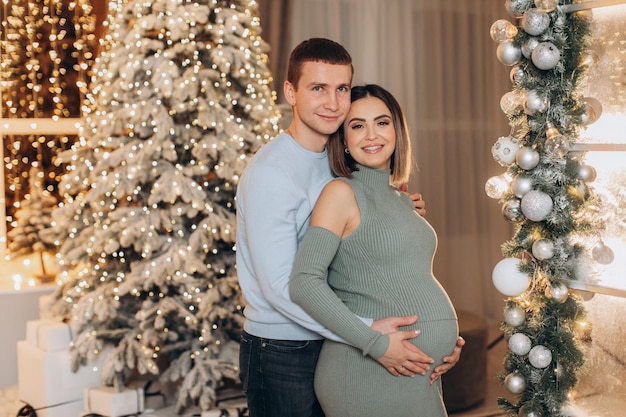 man hugging pregnant woman near Christmas tree