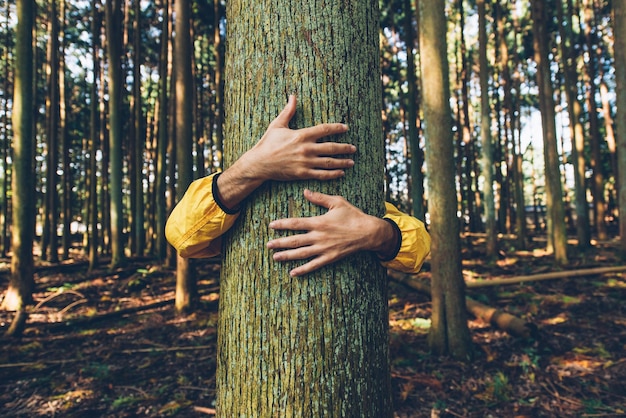 Photo man hugging tree trunk outdoors