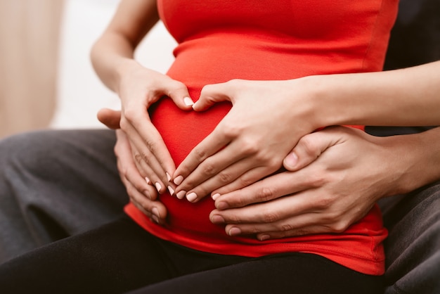 The man hugs the belly of his pregnant wife.