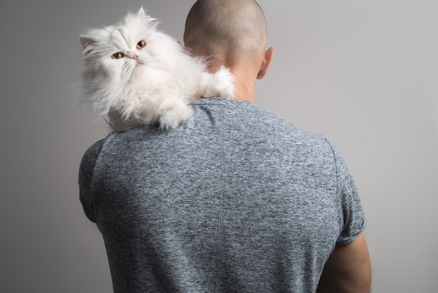 L'uomo abbraccia un grosso gatto persiano bianco. vista da dietro