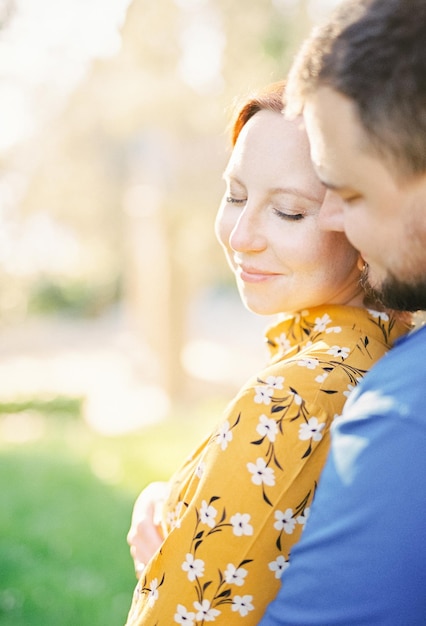 写真 庭の裏側の景色に立っている間に男は後ろから女性を抱きしめ鼻でに触れています