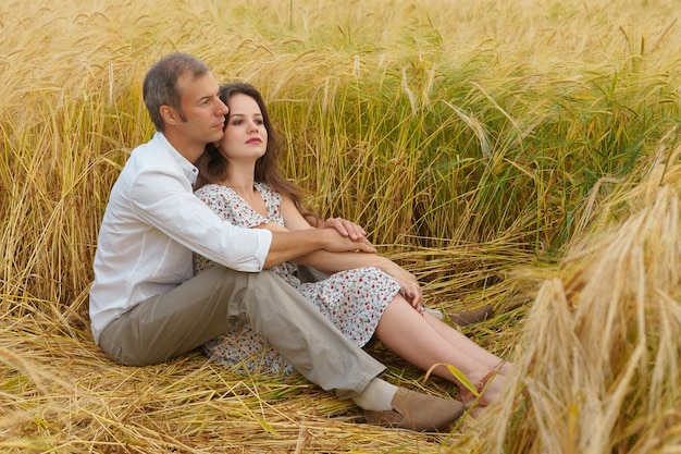L'uomo abbraccia la donna su un campo di grano, coppia d'amore, appuntamento romantico, famiglia felice