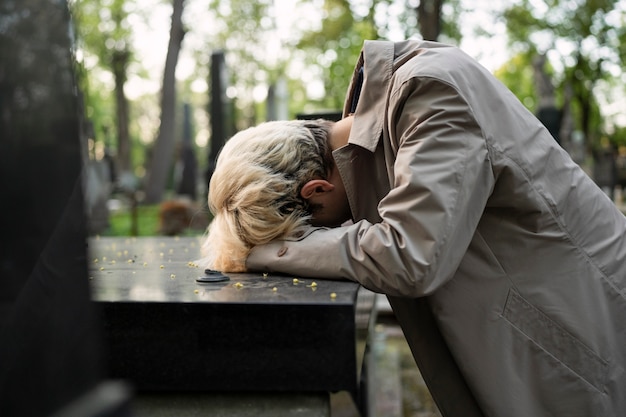 Foto man huilend over een graf op de begraafplaats