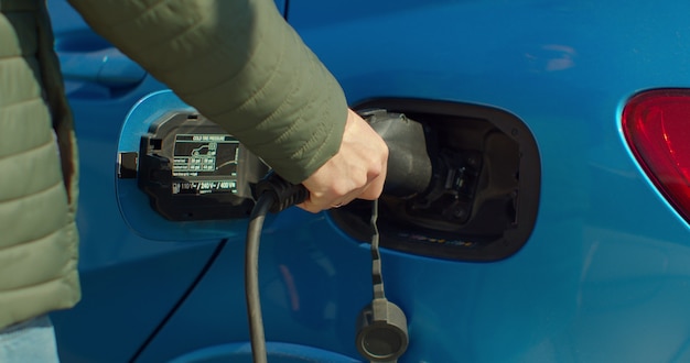 Man hybride auto thuis aansluiten op electro laadstation. Luxe blauwe elektrische auto opladen. Milieubewuste man zijn elektrische auto opladen.