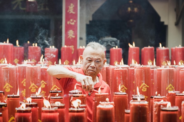 Photo man igniting candle in temple