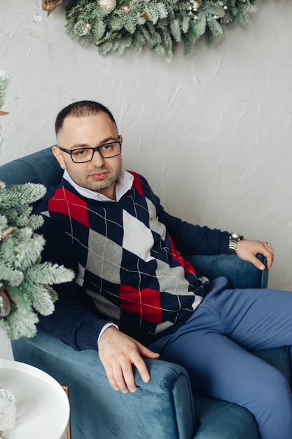 Man in argyle trui in fauteuil.