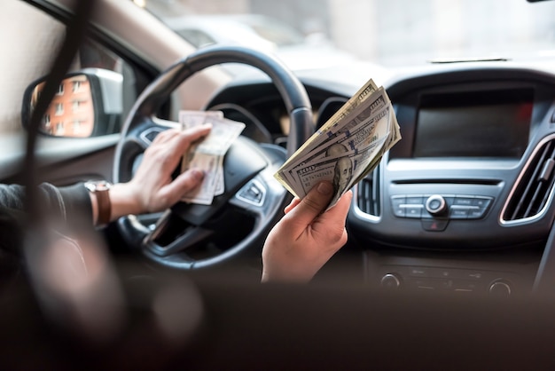 Man in auto met dollar voor steekpenningen of betalen in goederen. bedrijfsfinanciën concept