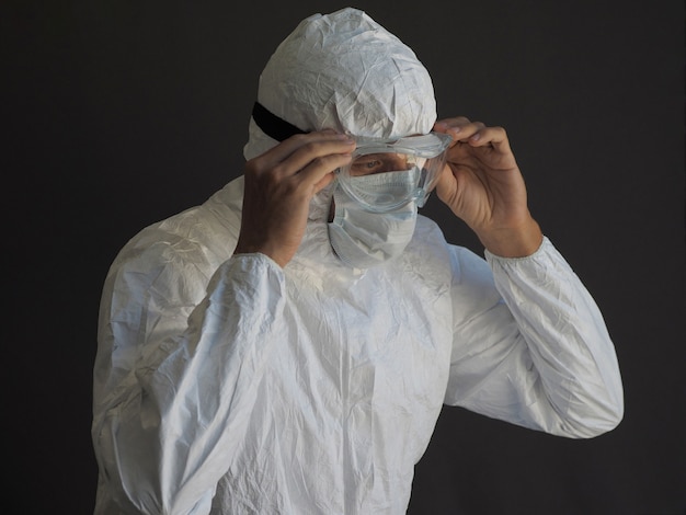 Foto man in beschermend pak en gezichtsmasker zet bril op