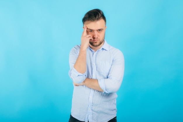 man in blauw shirt met gevouwen handen staat op blauwe achtergrond