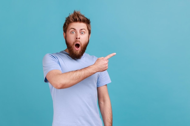 Man in blauwe tshirt wijzend opzij met lege kopie ruimte voor idee presentatie commerciële tekst