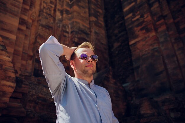 Фото Человек в голубой робе на фоне храма стены в солнцезащитные очки. концепция современной религии