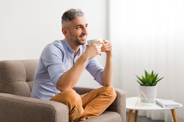 白いカップと笑顔を保持している青いシャツの男