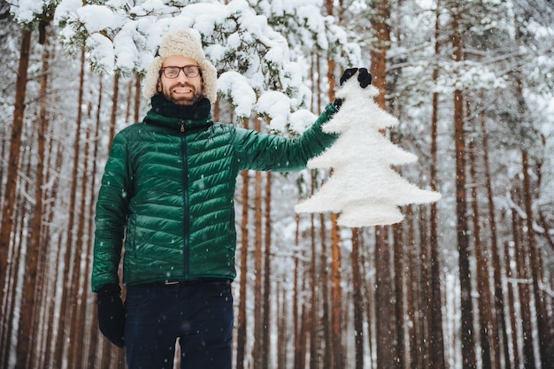 man in bontmuts met oorkleppen met een boom