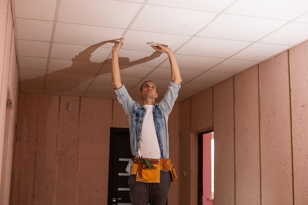 Man in bouwer uniforme hand omhoog installeren verlaagd plafond