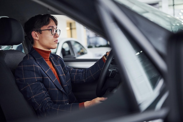 Man in brillen en formele kleding zit in moderne auto.