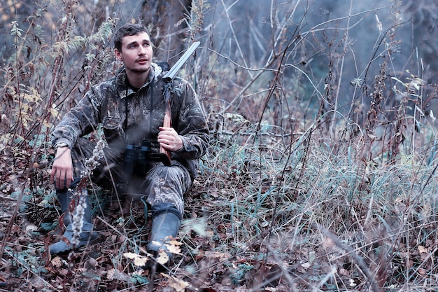 Man in camouflage en met een jachtgeweer in een bos op een lentejacht
