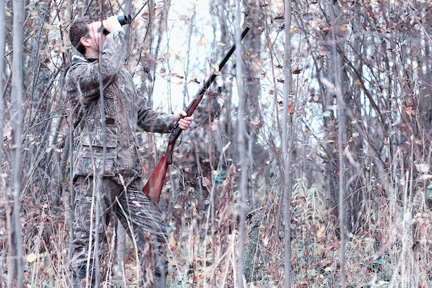 Man in camouflage en met een jachtgeweer in een bos op een lentejacht