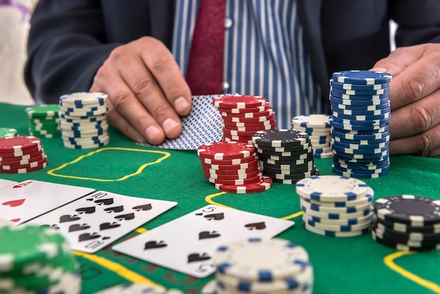 Man in casino kijken naar speelkaarten en stapel token chips