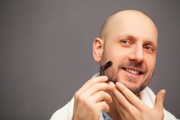 Man in de badkamer scheert zijn baard met een scheermes