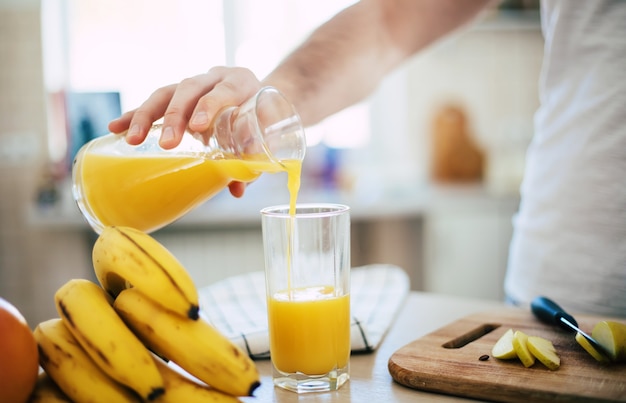 man in de keuken drinkt sinaasappelsap