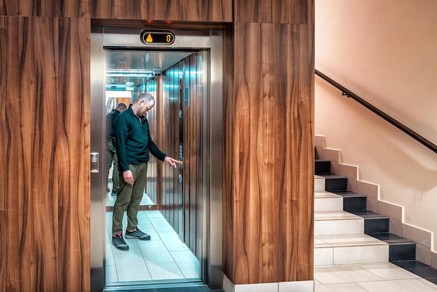 Man in de moderne lift drukt op een knop