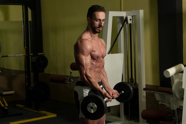 Man in de sportschool die biceps traint met barbell