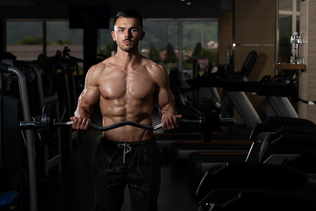 Man in de sportschool die biceps traint met barbell