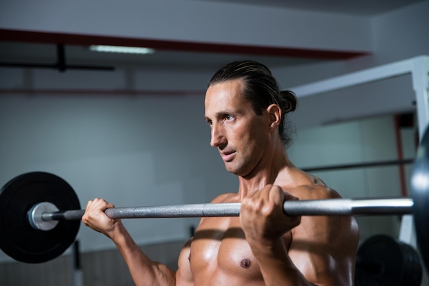 Man in de sportschool die biceps traint met barbell