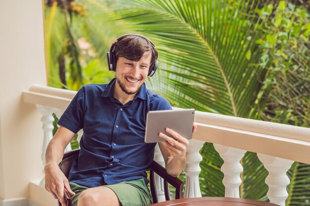 Man in de tropen die met vrienden en familie praat tijdens een videogesprek met een tablet en een draadloze hoofdtelefoon