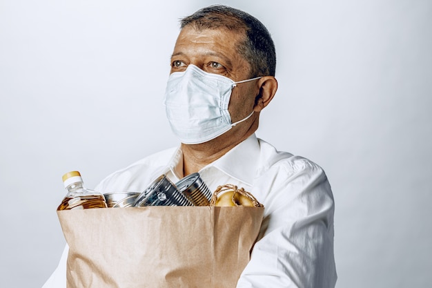 Man in een beschermende medische masker met een zak van een supermarkt