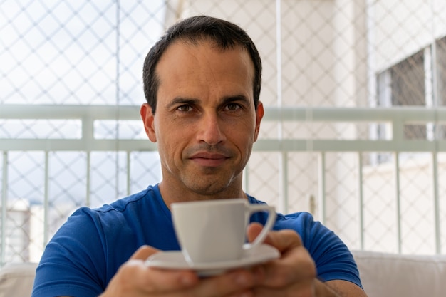 Man in een blauw shirt heeft een kopje koffie