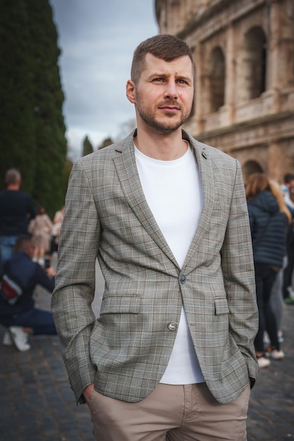 Man in een geruite blazer op een historische Europese locatie met geplaveide straat